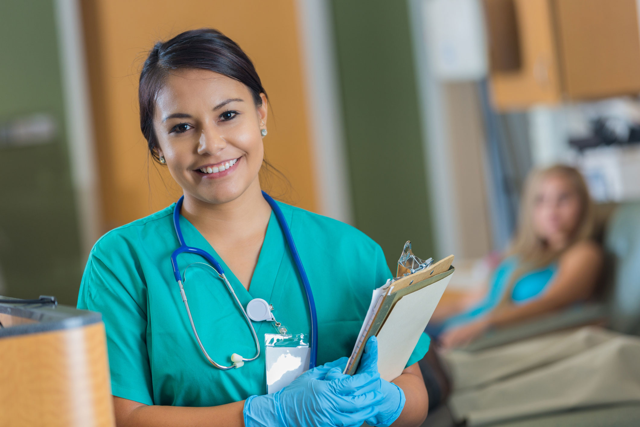 Dark haired girl in scrubs next to patient