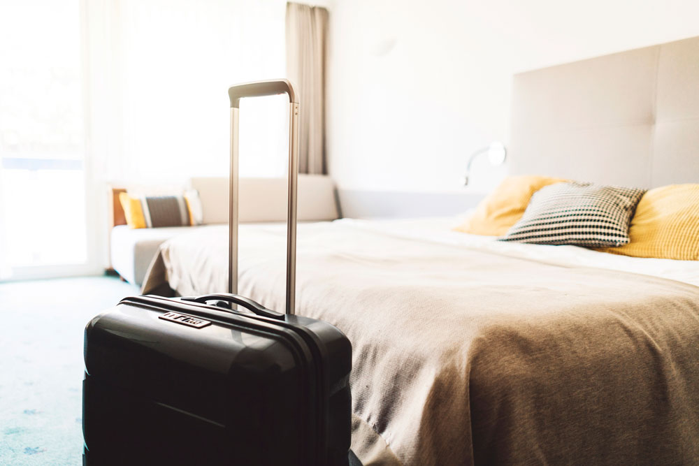 suitcase sitting at the end of bed in hotel room