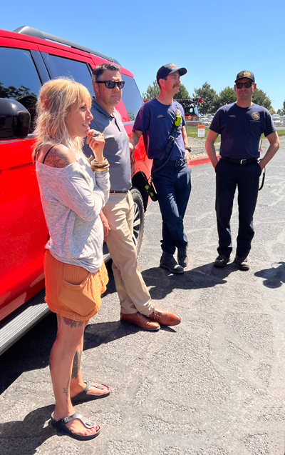 Emma Vlossak stands chatting with members of the Bend Fire and Rescue team