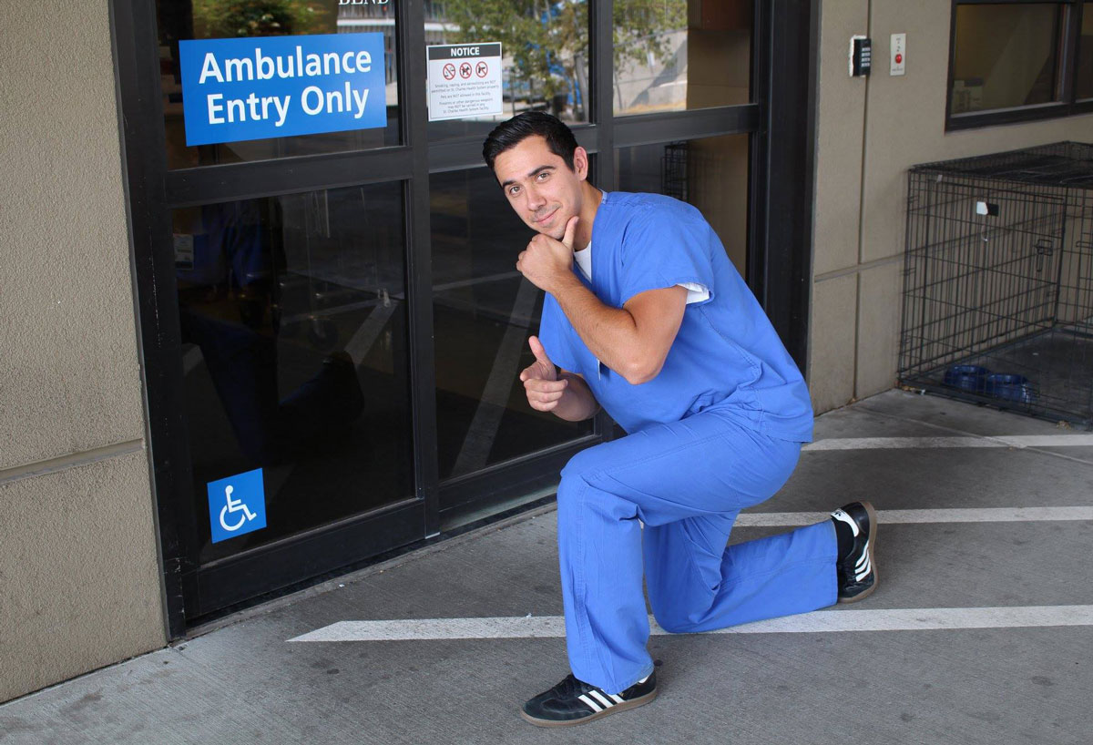 Man in scrubs squatted down next to ER doors