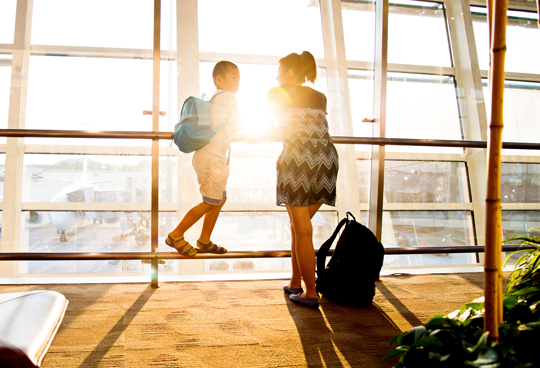 mom and son standing near windows of airport