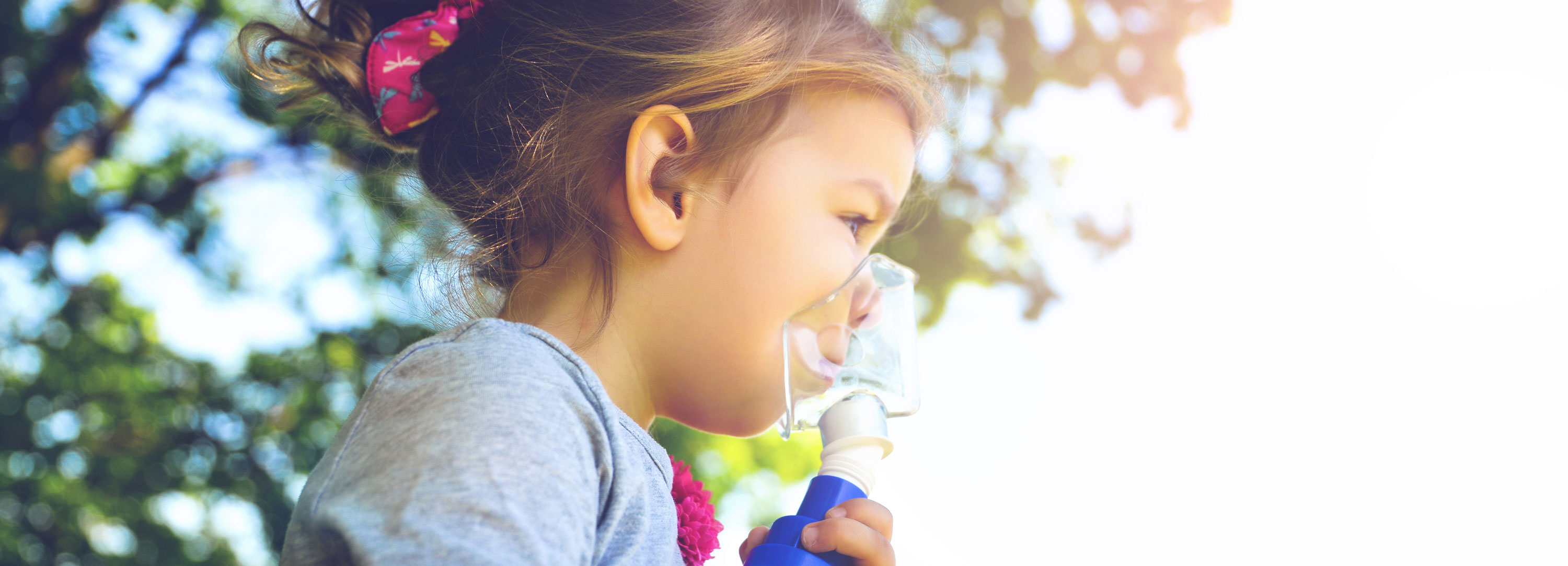 little girl holding asthma inhaler up to nose