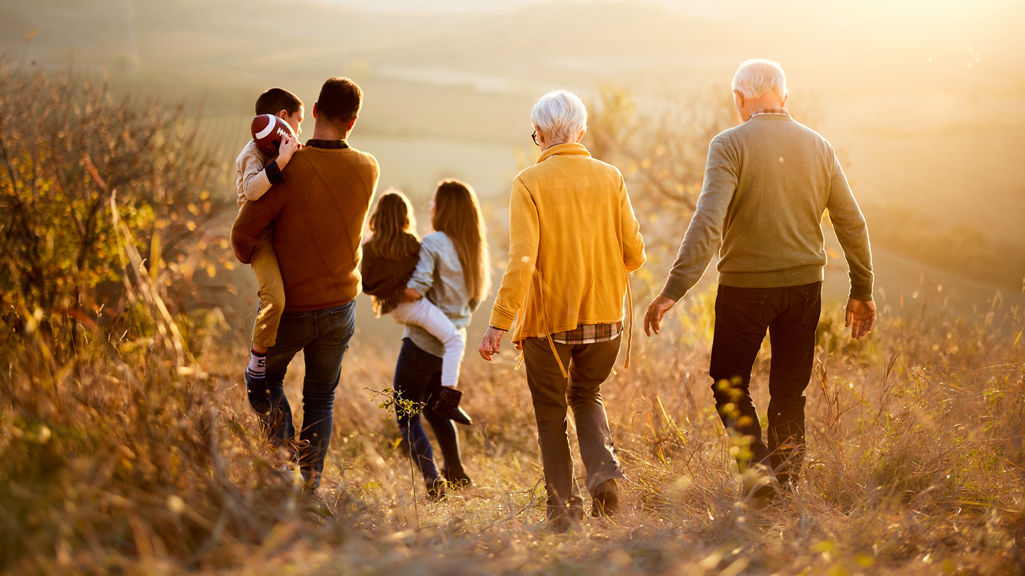 multi-generational family walking on a hillside in the autumn sun