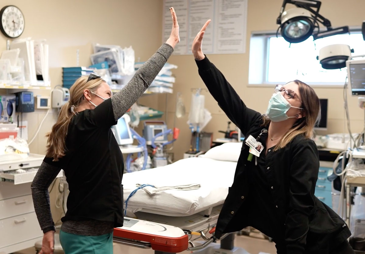 Two St. Charles caregivers air high-fiving in a patient room
